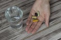 Close-up of a hand holding pills and a glass of water. Nutritional supplements. Sport, diet concept. Capsules, healthy lifestyle Royalty Free Stock Photo