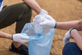 Close up hand holding plastic bottle put in garbage bag, Group of volunteer young people collecting plastic water bottles into Royalty Free Stock Photo