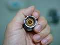 A hand holding a removed / disassembled part of a rain shower head getting clogged with mineral deposits