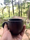 Hand Holding Black Ceramic Coffee Cup in Forest Nature Background Royalty Free Stock Photo
