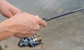 Close-up of a hand holding a spinning rod and turning a reel. A fisherman with a fishing rod. Man fishing. Free time concept Royalty Free Stock Photo