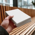 A Close-Up of a Hand Holding a Stack of Blank Papers on a Stylish Wooden Bench in a Modern Setting Royalty Free Stock Photo