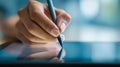 Close-up of a hand holding a stylus pen and interacting with a digital tablet screen for creative design or note-taking in a Royalty Free Stock Photo