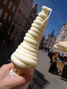 Close up a hand holding tall twist shape soft cream in waffle cone on summer, blurry background