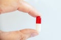 Close up of a hand holding a white and red pill, health medication concept Royalty Free Stock Photo