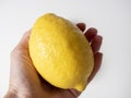 Close-up of a hand holding a yellow lemon. White background, side view Royalty Free Stock Photo