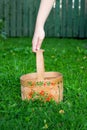 Close-up hand holds russian domestic birch bast basket with Khokhloma traditional painting on it on green grass and fence