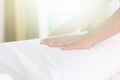 Hand of housekeeper set up white pillow on the bed sheet in hotel room at morning time with sunlight from windows Royalty Free Stock Photo