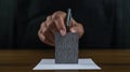 Close-up of a hand inserting a ballot into a box, symbolizing voting, elections, and democratic participation in a formal setting Royalty Free Stock Photo