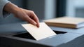 Close-up of hand inserting envelope into black ballot box during voting process in modern indoor setting Royalty Free Stock Photo