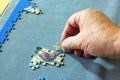 Close up of a hand inserting a piece of jigsaw puzzle.