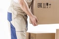 Close-up of hand of loader holding cardboard box isolated on white background. Loader picks up box. Mover holds cardboard box Royalty Free Stock Photo