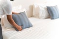 Close up hand of maid setting up pillow on bed sheet in hotel room Royalty Free Stock Photo