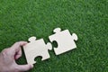 Close up hand of man connecting jigsaw puzzle on grass background Royalty Free Stock Photo