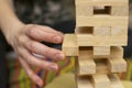 Hand of a man, a girl, pulls a piece of wooden bar from the tower structure of a toy house Royalty Free Stock Photo