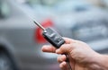 Close up hand of Man holding car key  with blurred car on background. hand presses on the remote control car alarm systems. Royalty Free Stock Photo
