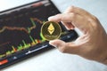 Close-up hand of man holding crypto coin on chart in tablet background. Blockchain technology finance future. Male hold Ethereum.