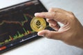 Close-up hand of man holding crypto coin on chart in tablet background. Blockchain technology finance future. Male hold Ethereum.