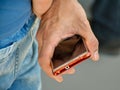 close up of the hand of a man holding his phone between his finger. The man ÃÂ´s hand is at his back. He is no using his mobile Royalty Free Stock Photo