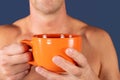 Close up of a hand of man holding a orange coffee cup on blue background Royalty Free Stock Photo