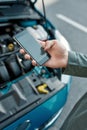 Close up of hand of man holding phone, calling emergency car service while standing near his broken car with open hood Royalty Free Stock Photo