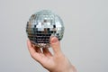 Close-up hand of a man holding a silver mirror party ball . Concept regarding parties after the covid-19 isolation