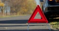 Close up hand of man putting warning triangle by the broken car on a road. Concept road accident. Help repair. Royalty Free Stock Photo