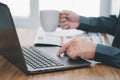 Close up hand a man touch on mouse pad of laptop and hold coffee cup Royalty Free Stock Photo