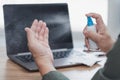 Close up hand a man use alcohol bottle spray clean hand and laptop computer on the table primary disease prevention