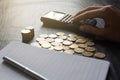 Close up hand of man using  calculator with gold coins, pen, notebook on black table. Business, finance, marketing, e-commerce Royalty Free Stock Photo