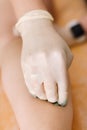 Close-up of a hand that applies a lump of sugar paste for sugaring to the client& x27;s body
