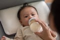 Close up hand of mother holding milk bottle Newborn baby lying on bed drinking milk.Cute infant baby feeding milk with love at Royalty Free Stock Photo
