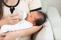 Close up hand of mother holding milk bottle Newborn baby lying on bed drinking milk at warmth place. Cute infant baby feeding milk Royalty Free Stock Photo