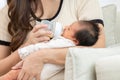 Close up hand of mother holding milk bottle Newborn baby lying on bed drinking milk at warmth place. Cute infant baby feeding milk Royalty Free Stock Photo