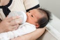 Close up hand of mother holding milk bottle Newborn baby lying on bed drinking milk at warmth place. Cute infant baby feeding milk Royalty Free Stock Photo