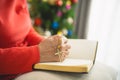 Close up hand. old senior woman doing hands together and holding necklace of crosses prayer to God along with the bible In the Royalty Free Stock Photo