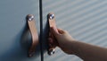 Close up hand open wooden cabinet. shades from blinds on cabinet doors. Royalty Free Stock Photo