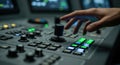 Close up of a hand operating a complex broadcast mixing console with illuminated buttons and faders Royalty Free Stock Photo
