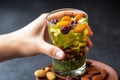close-up of hand over a glass of iced matcha tea topped with dried fruits