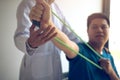 Close up hand patient doing stretching exercise with a flexible exercise band and a physical therapist hand to help in clinic room Royalty Free Stock Photo