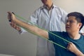 Close up hand patient doing stretching exercise with a flexible exercise band and a physical therapist hand to help in clinic room