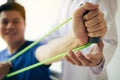 Close up hand patient doing stretching exercise with a flexible exercise band and a physical therapist hand to help in clinic room Royalty Free Stock Photo