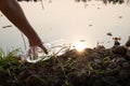 Hand picking up a clear plastic bottle drop on the ground with polluted water background Royalty Free Stock Photo