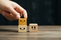 Close up A hand picks a smiley face from wooden cube service rating