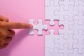 Close up of hand placing the last jigsaw puzzle piece on pink ba Royalty Free Stock Photo