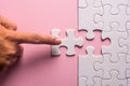 Close up of hand placing the last jigsaw puzzle piece on pink ba Royalty Free Stock Photo