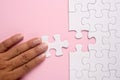 Close up of hand placing the last jigsaw puzzle piece on pink ba Royalty Free Stock Photo