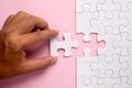 Close up of hand placing the last jigsaw puzzle piece on pink ba Royalty Free Stock Photo
