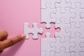 Close up of hand placing the last jigsaw puzzle piece on pink ba Royalty Free Stock Photo