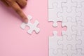 Close up of hand placing the last jigsaw puzzle piece on pink ba Royalty Free Stock Photo